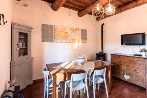 uma sala de jantar com mesa e cadeiras e uma televisão em Le Stanze del Ciondolo em Montepulciano