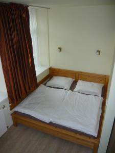 uma cama com lençóis brancos e almofadas num quarto em Apartmány Liška em Mladé Buky