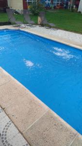 una piscina azul con sillas en un patio en Cabañas El Paraiso in 