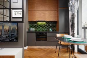 a kitchen with a table with chairs and a stove at Apartments Konstruktorska by Renters Prestige in Warsaw