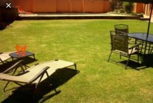 un par de mesas y sillas en un patio en SunSet West Self Catering Maraisburg Roodepoort en Johannesburgo