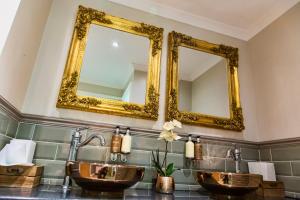 two sinks in a bathroom with two mirrors at The Ship Inn in Dymchurch