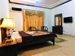 a bedroom with a bed and a table and a television at High Trees Inn in Islamabad