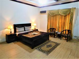1 dormitorio con 1 cama, 2 sillas y ventana en High Trees Inn, en Islamabad