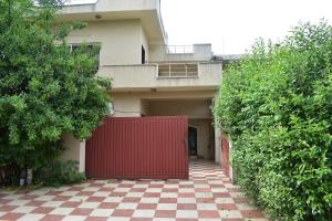 un cancello rosso di fronte a una casa con pavimento a scacchi di High Trees Inn a Islamabad