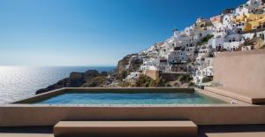 a swimming pool on the side of a hill next to the ocean at Old Castle Oia in Oia