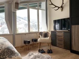 a bedroom with a bed and a chair and a tv at Apartment Lausbuam in Mühlbach am Hochkönig