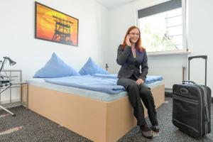 Eine Frau, die auf einem Bett mit einem Koffer sitzt. in der Unterkunft Boardinghouse Gladbeck in Gladbeck