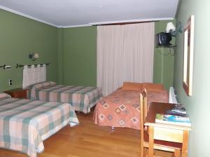 2 Betten in einem Zimmer mit grünen Wänden und einem Tisch in der Unterkunft Hostal-Restaurante San Antolín in Tordesillas