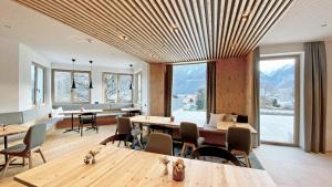 a restaurant with wooden tables and chairs and windows at Thalers Mariandl in Schladming