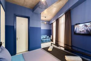 第比利斯Modern Avlabari in Old Town的一间卧室设有蓝色的墙壁和平面电视。