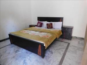 a bedroom with a large bed with a wooden headboard at AB Guesthouse in Rawalpindi