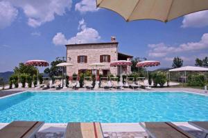 a pool with chairs and umbrellas in front of a building at Appartamento Corallo in Cagli