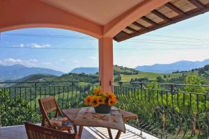 a table and chairs on a balcony with a view of mountains at Casale La Veduta in Acqualagna