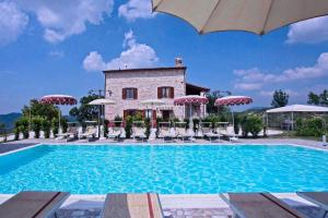 - une piscine avec des chaises et des parasols en face d'un bâtiment dans l'établissement Appartamento Indaco, à Cagli