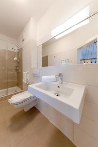 a white bathroom with a sink and a toilet at Hotel Glückauf 1908 in Ostseebad Sellin