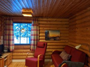 Sala de estar de una cabaña de madera con sofá y ventana en Tunturioravat, en Äkäslompolo