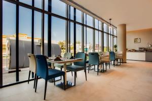a restaurant with tables and chairs and large windows at Lemon Tree Hotel, Jumeirah Dubai in Dubai