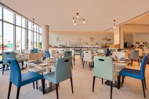 a restaurant with white tables and blue chairs at Lemon Tree Hotel, Jumeirah Dubai in Dubai