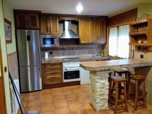 a kitchen with wooden cabinets and a stainless steel refrigerator at Tinao de Gredos in Navarredonda de Gredos