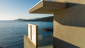 a window on a building with a view of the water at Hotel le Jardin d'Emile in Porticcio