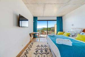 a bedroom with a large blue bed and a balcony at Hotel le Jardin d'Emile in Porticcio