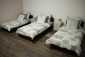 three beds in a room with wood floors at Alex Lodge in Zrenjanin
