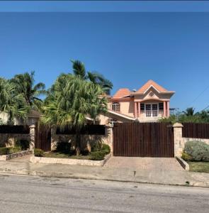 a pink house with a fence and palm trees at Jobs Inn Jamaica in Montego Bay