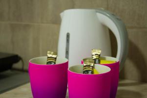 two pink cups with gold bars in them next to a kettle at Alex Lodge in Zrenjanin