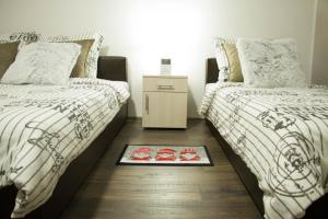 a bedroom with two beds and a rug on the floor at Alex Lodge in Zrenjanin