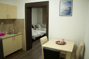 a kitchen and dining room with a table and a room with a bed at Alex Lodge in Zrenjanin