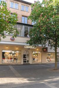 ein Geschäft vor einem Gebäude mit einem Baum davor in der Unterkunft Boardinghouse Gladbeck in Gladbeck