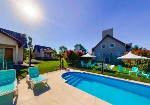 ein Swimmingpool mit Stühlen und Sonnenschirmen neben einem Haus in der Unterkunft Cabañas Brisas del Cerro in Los Reartes