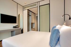 Lemon Tree Hotel, Jumeirah Dubai في دبي: غرفة نوم بسرير ابيض كبير وتلفزيون