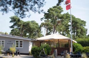 un patio con sombrilla y sillas y un edificio en Dueodde Hostel en Neksø