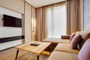 a living room with a couch and a tv at Lemon Tree Hotel, Jumeirah Dubai in Dubai