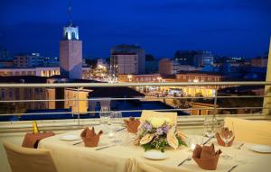 una mesa con copas de vino y flores en el balcón en Hotel Europa, en Latina