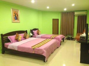 two beds in a room with green walls at Penang Palace in Bangkok