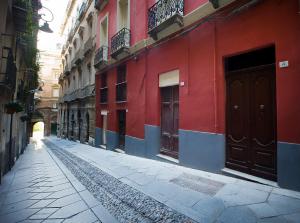 una calle vacía con un edificio rojo con puertas en Castelletto Suites, en Cagliari