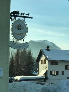 a sign in front of a building in the snow at DEVA Hotel-Restaurant Fischerwirt inklusive Chiemgau Card in Ruhpolding