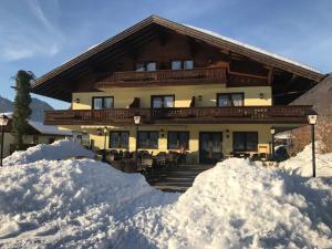 a large house with snow piled up in front of it at DEVA Hotel-Restaurant Fischerwirt inklusive Chiemgau Card in Ruhpolding