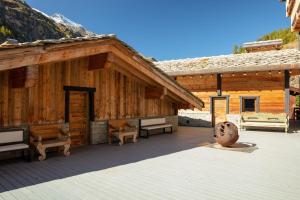a large wooden building with a deck with benches at Chalet Carte Blanche Raven in Tignes