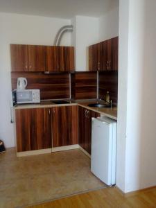 a kitchen with wooden cabinets and a sink and a refrigerator at Dima Popova Apartments in Tsarevo