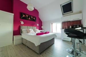 マンチェスターにあるRegency Guesthouse Manchesterのピンクの壁のベッドルーム1室(大型ベッド1台付)