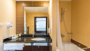 uma casa de banho com um lavatório, um chuveiro e um espelho. em Qubus Hotel Kraków em Cracóvia