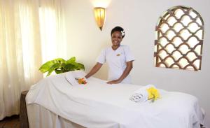 a man is standing next to a bed at Severin Sea Lodge in Mombasa