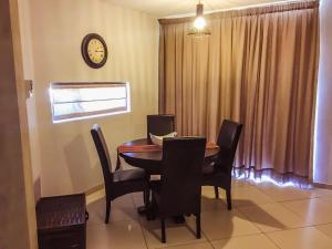 a dining room with a table and chairs and a clock at Elegant Apartment at Grove Mall in Windhoek