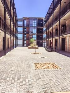 an empty courtyard of a building with a tree in the middle at Elegant Apartment at Grove Mall in Windhoek