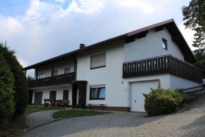 a white house with a balcony and a table at Ferienwohnung- Pfenniggeiger in Philippsreut