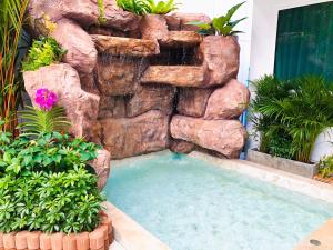 a swimming pool in front of a rock wall with a waterfall at Peranakan House - SHA Plus in Phuket